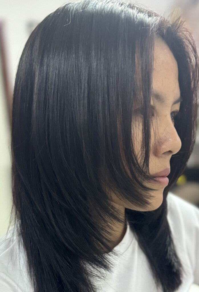 Friendly hairdresser in Chiang Mai styling a customer's hair at Praewa's Beauty Salon